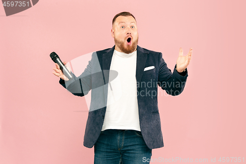 Image of Young man with microphone on pink background, leading with microphone