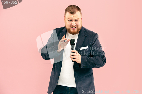 Image of Young man with microphone on pink background, leading with microphone