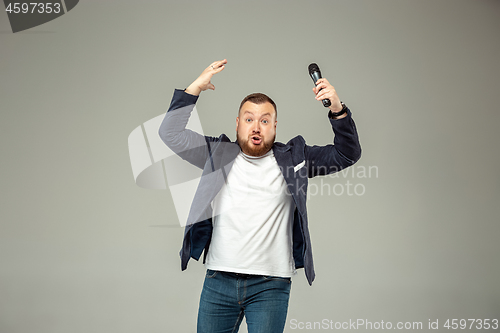 Image of Young man with microphone on gray background, leading with microphone