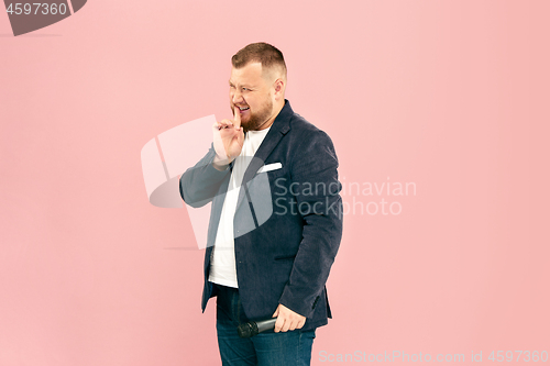 Image of Young man with microphone on pink background, leading with microphone