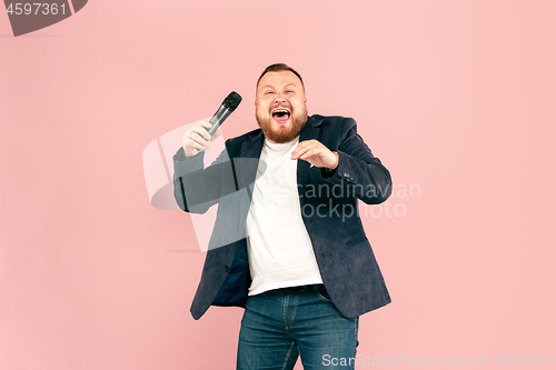 Image of Young man with microphone on pink background, leading with microphone