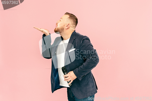 Image of Young man with microphone on pink background, leading with microphone