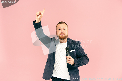 Image of Young man with microphone on pink background, leading with microphone