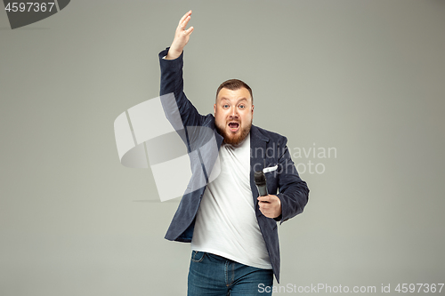 Image of Young man with microphone on gray background, leading with microphone