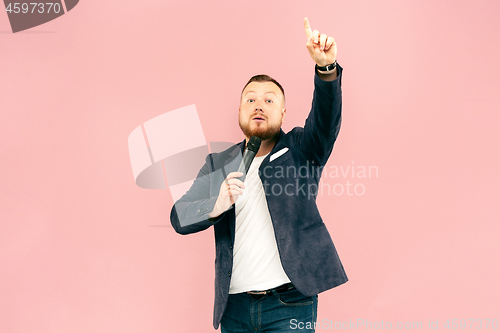 Image of Young man with microphone on pink background, leading with microphone