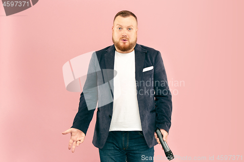 Image of Young man with microphone on pink background, leading with microphone