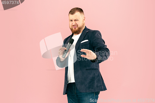 Image of Young man with microphone on pink background, leading with microphone