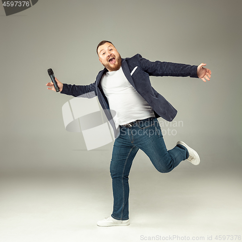 Image of Young man with microphone on gray background, leading with microphone