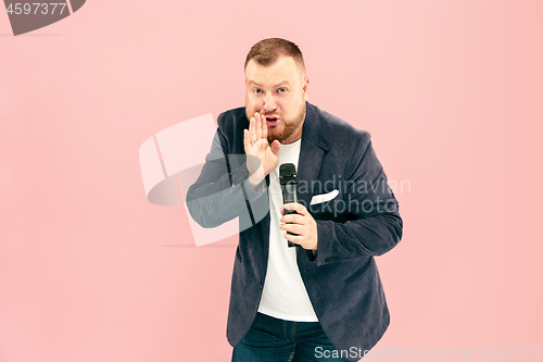 Image of Young man with microphone on pink background, leading with microphone