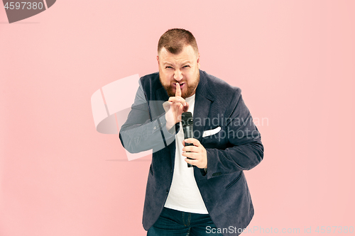 Image of Young man with microphone on pink background, leading with microphone