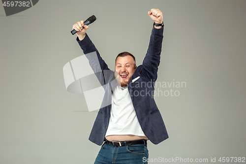 Image of Young man with microphone on gray background, leading with microphone