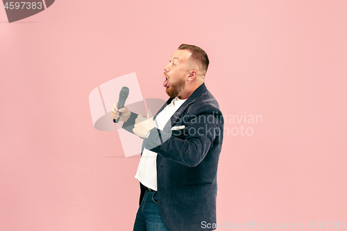 Image of Young man with microphone on pink background, leading with microphone