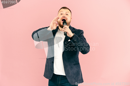 Image of Young man with microphone on pink background, leading with microphone
