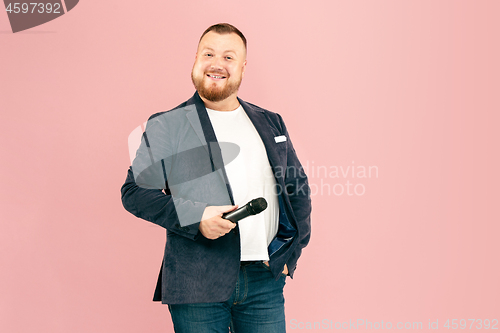 Image of Young man with microphone on pink background, leading with microphone