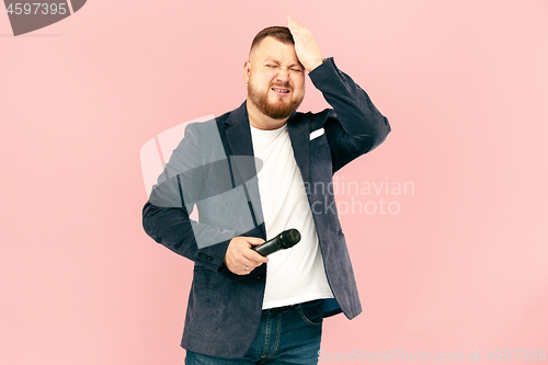 Image of Young man with microphone on pink background, leading with microphone