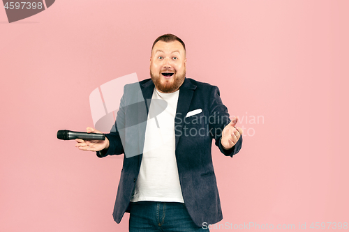 Image of Young man with microphone on pink background, leading with microphone
