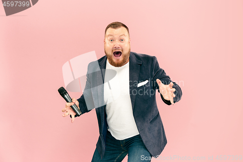 Image of Young man with microphone on pink background, leading with microphone