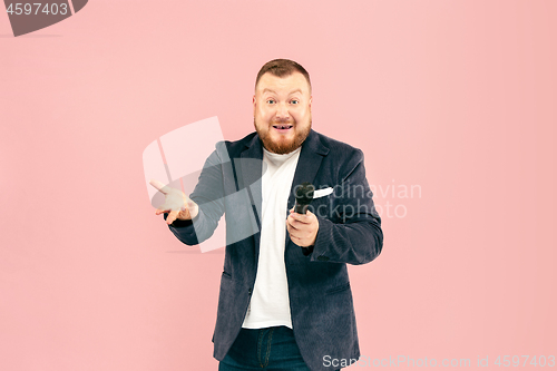 Image of Young man with microphone on pink background, leading with microphone