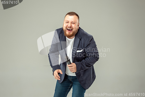 Image of Young man with microphone on gray background, leading with microphone