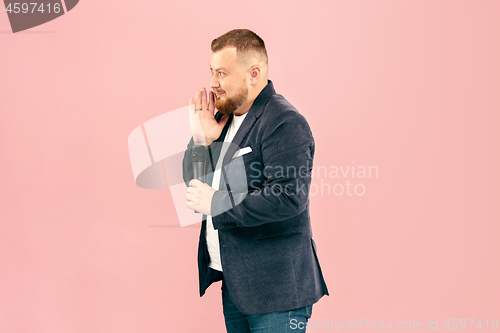 Image of Young man with microphone on pink background, leading with microphone