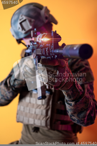 Image of soldier in action aiming laseer sight optics yellow background