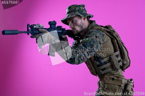 Image of soldier in action aiming laseer sight optics pink background
