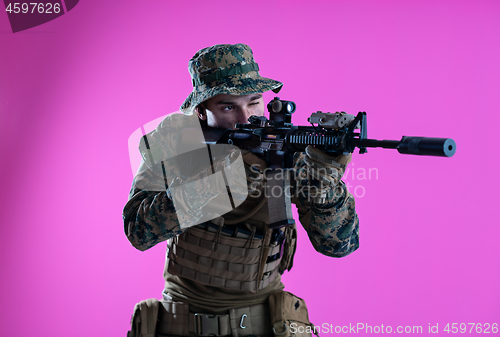 Image of soldier in action aiming laseer sight optics pink background