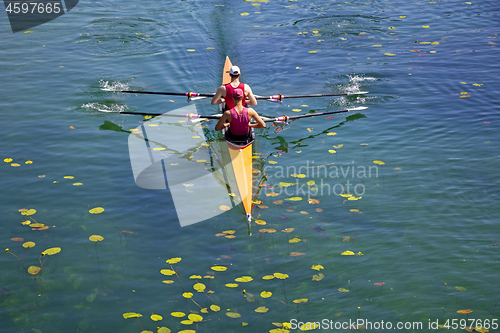 Image of Two young athletes rowing team on green lake