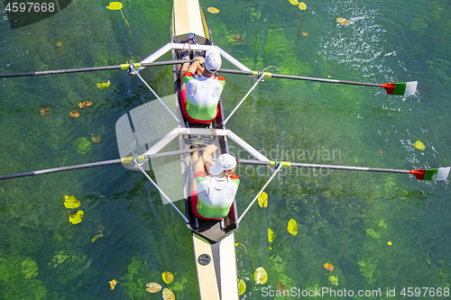 Image of Two young athletes rowing team on green lake