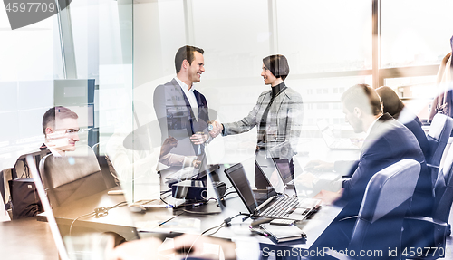 Image of Confident business people shaking hands in moder corporate office.