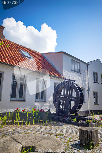 Image of Water mill with flowers on a terrace in a backyard