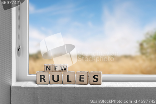 Image of New rules sign in a window with a view to fields