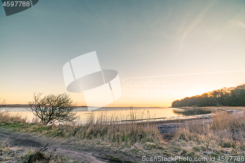 Image of Sunrise over a lake in the winter with frost