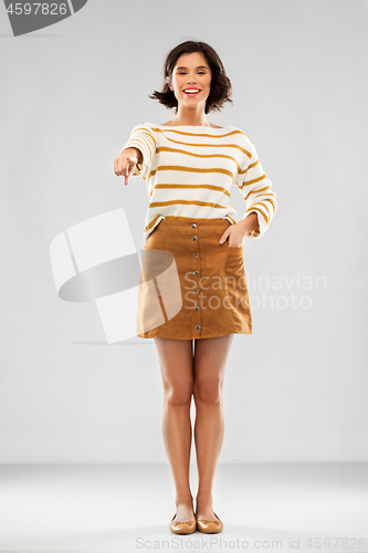 Image of woman in pullover, skirt and shoes pointing to you