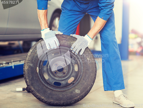 Image of mechanic with wheel tire at car workshop