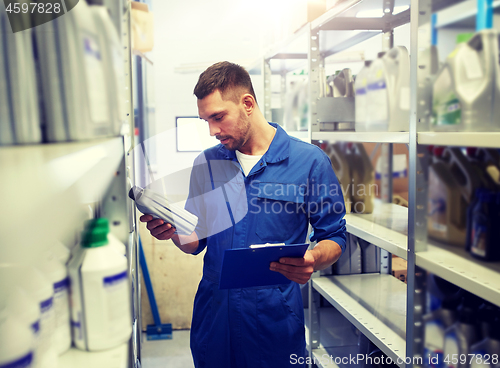 Image of auto mechanic with oil and clipboard at car shop