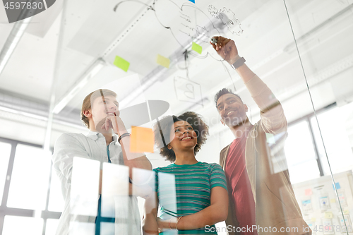 Image of happy creative team at office glass board