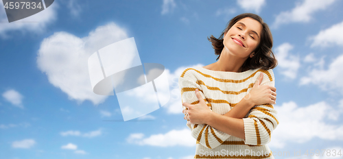 Image of woman hugging herself over heart shaped cloud