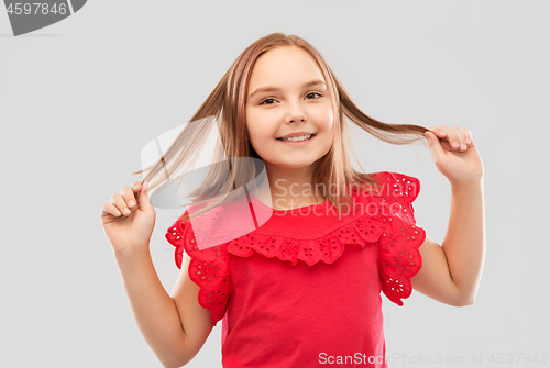 Image of happy girl in red shirt with holding hair strands