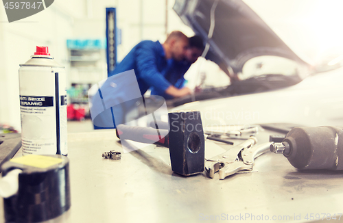 Image of working tools and men repairing car at workshop