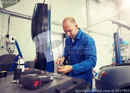 Image of mechanic man with wrench repairing car at workshop