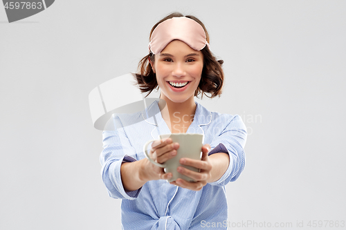 Image of woman in pajama and sleeping mask drinking coffee