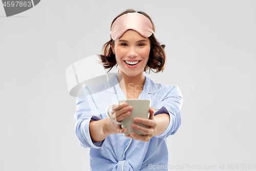 Image of woman in pajama and sleeping mask drinking coffee