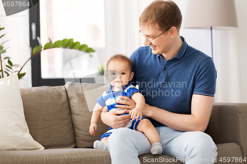 Image of happy father with baby son sitting on sofa at home