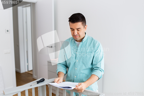 Image of father with manual assembling baby bed at home