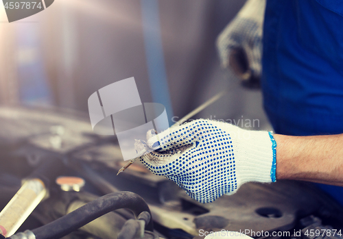 Image of mechanic with dipstick checking motor oil level