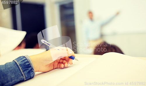 Image of student hand writing to notebook at lecture