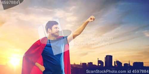 Image of man in red superhero cape over sunset in city