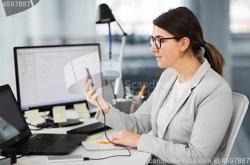 Image of businesswoman charging smartphone by power bank