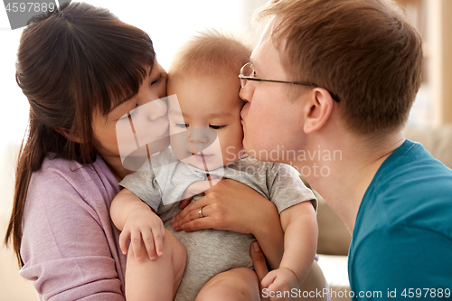 Image of happy mother and father kissing baby son at home